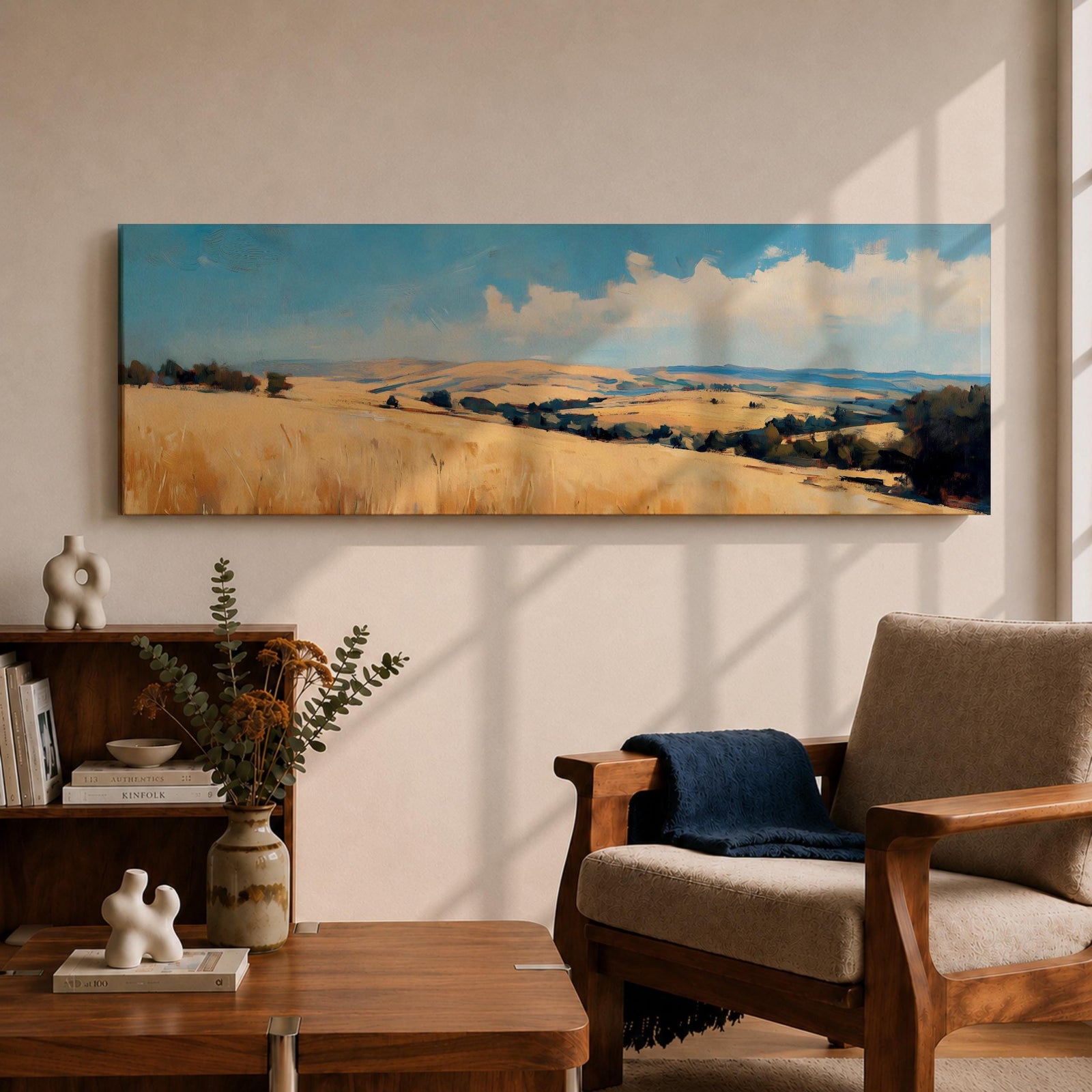 Panoramic wheat field landscape painting showing rolling golden farmland stretching across hills beneath a bright blue sky with scattered clouds. Textured brushstrokes depict tall wheat grasses in the foreground leading toward layered countryside fields, tree clusters, and distant hills across the wide rural horizon.