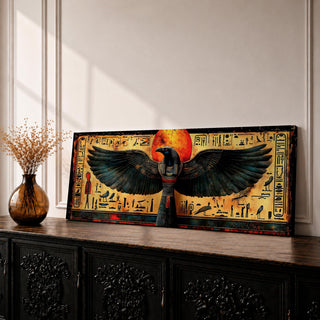 Panoramic ancient Egyptian style artwork featuring the falcon headed god Horus with wide outstretched wings beneath a glowing red sun disk. Hieroglyphic symbols and figures frame the composition while textured gold and dark tones highlight the wings and central deity across the wide symmetrical scene.