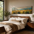Panoramic wildflower meadow painting featuring tall golden grasses mixed with scattered red, yellow, and blue flowers swaying across an open field. Loose textured brushstrokes create depth through the meadow while a soft blue sky and distant horizon stretch across the wide landscape composition.
