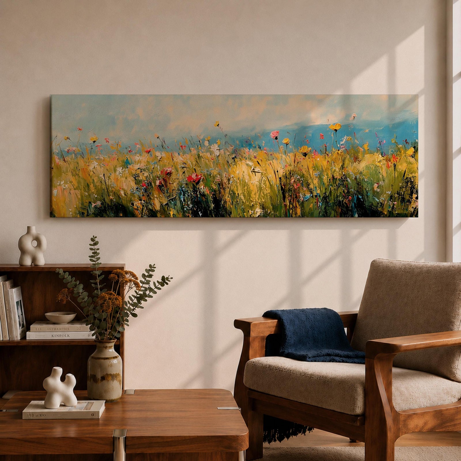 Panoramic wildflower meadow painting featuring tall golden grasses mixed with scattered red, yellow, and blue flowers swaying across an open field. Loose textured brushstrokes create depth through the meadow while a soft blue sky and distant horizon stretch across the wide landscape composition.