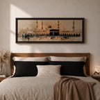 Panoramic painting of the Kaaba at Masjid Al Haram in Mecca surrounded by mosque arches and tall minarets. The sacred black cube stands at the center of a wide courtyard with crowds gathered around while warm golden tones and architectural details stretch across the expansive skyline.