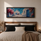 Panoramic painting of a Santorini village featuring whitewashed buildings with blue doors and a domed church along a sunlit stone pathway. Pink bougainvillea flowers frame the scene while bright blue sky and distant Aegean Sea appear beyond the island architecture across the wide composition.