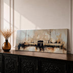 Panoramic painting of the Kaaba at Masjid al Haram with surrounding mosque arches and minarets, rendered in a loose abstract style with warm beige, brown, and black tones. The composition stretches horizontally with expressive brush textures, architectural silhouettes, and layered strokes highlighting the Kaaba at the center of the sacred mosque complex.