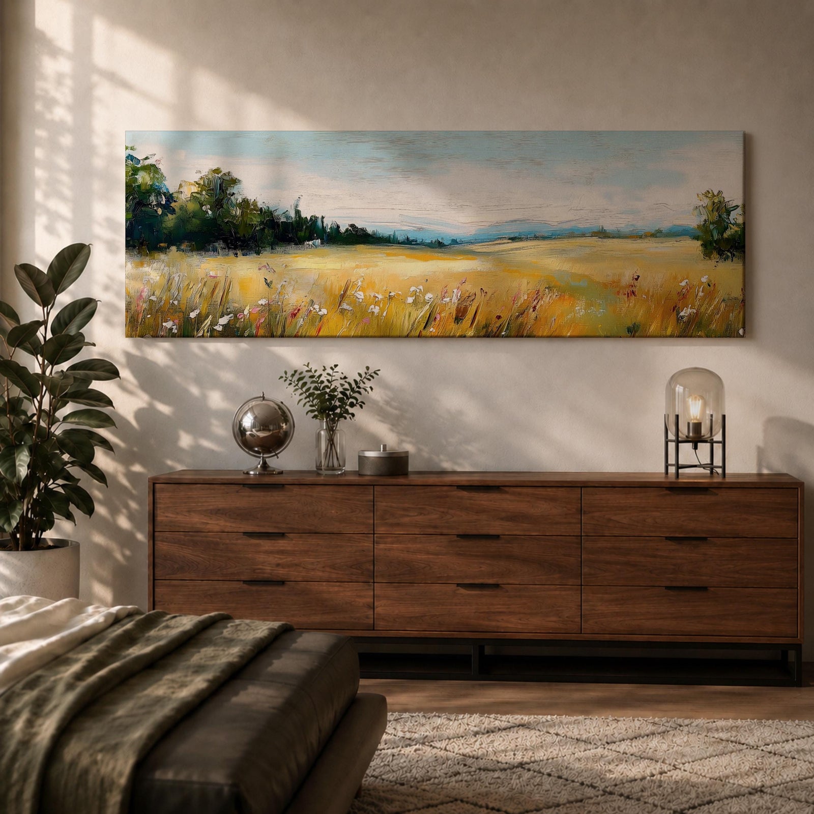 Panoramic countryside landscape painting showing a wide golden field filled with tall grasses and scattered wildflowers. A tree line borders the meadow while distant hills stretch across the horizon beneath a soft blue sky with light clouds across the expansive rural scene.