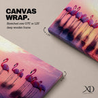 Panoramic artwork showing a flock of flamingos standing in shallow reflective water at sunset. The long horizontal composition features pink birds mirrored in the calm lake surface with glowing orange, purple, and magenta sky tones behind them, creating a tropical waterscape with silhouettes and soft reflections stretching across the scene.
