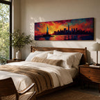 Panoramic cityscape painting showing the Statue of Liberty standing in the harbor with the New York City skyline stretching across the horizon, including tall skyscrapers and One World Trade Center, illuminated by a dramatic sunset sky filled with vibrant red, orange, and blue clouds reflected in the water.
