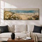 A long panoramic coastal painting showing sandy dunes covered with wild grasses and small white flowers overlooking a calm ocean shoreline. Soft waves roll toward the beach beneath a pale blue sky while textured brush strokes create a peaceful seascape landscape stretching across a wide horizontal composition.