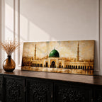 A long panoramic painting of the Prophet’s Mosque in Medina featuring the iconic green dome centered above grand archways and courtyards. Tall minarets rise on both sides while warm golden tones and textured brush strokes depict the historic Islamic mosque complex in a wide horizontal architectural composition.