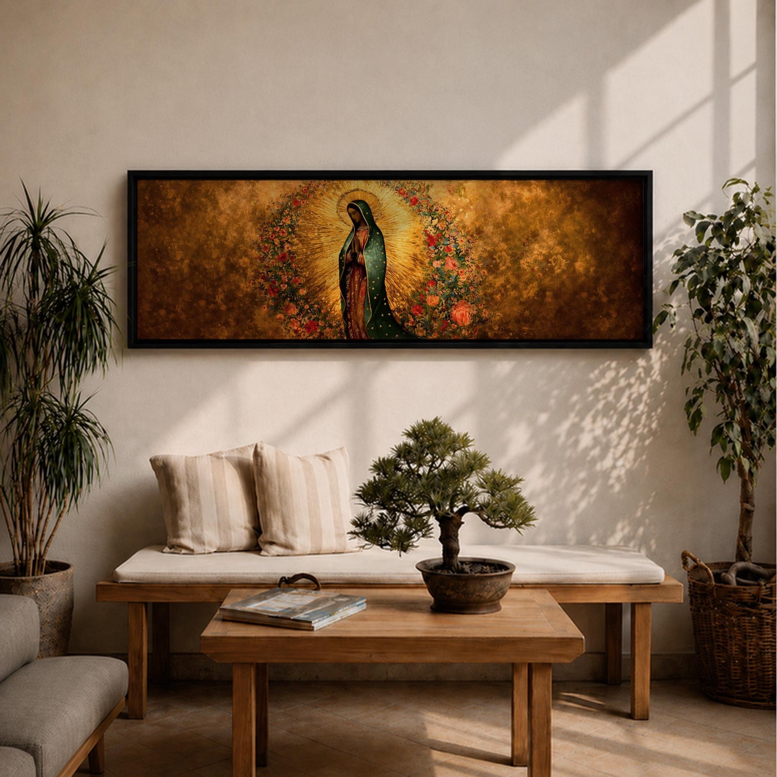 A long panoramic artwork depicting Our Lady of Guadalupe standing in prayer with folded hands and bowed head. She wears a green star covered mantle over a rose colored gown and is surrounded by radiant golden rays and a wreath of vibrant flowers, forming a traditional Catholic Marian image in a wide horizontal composition.