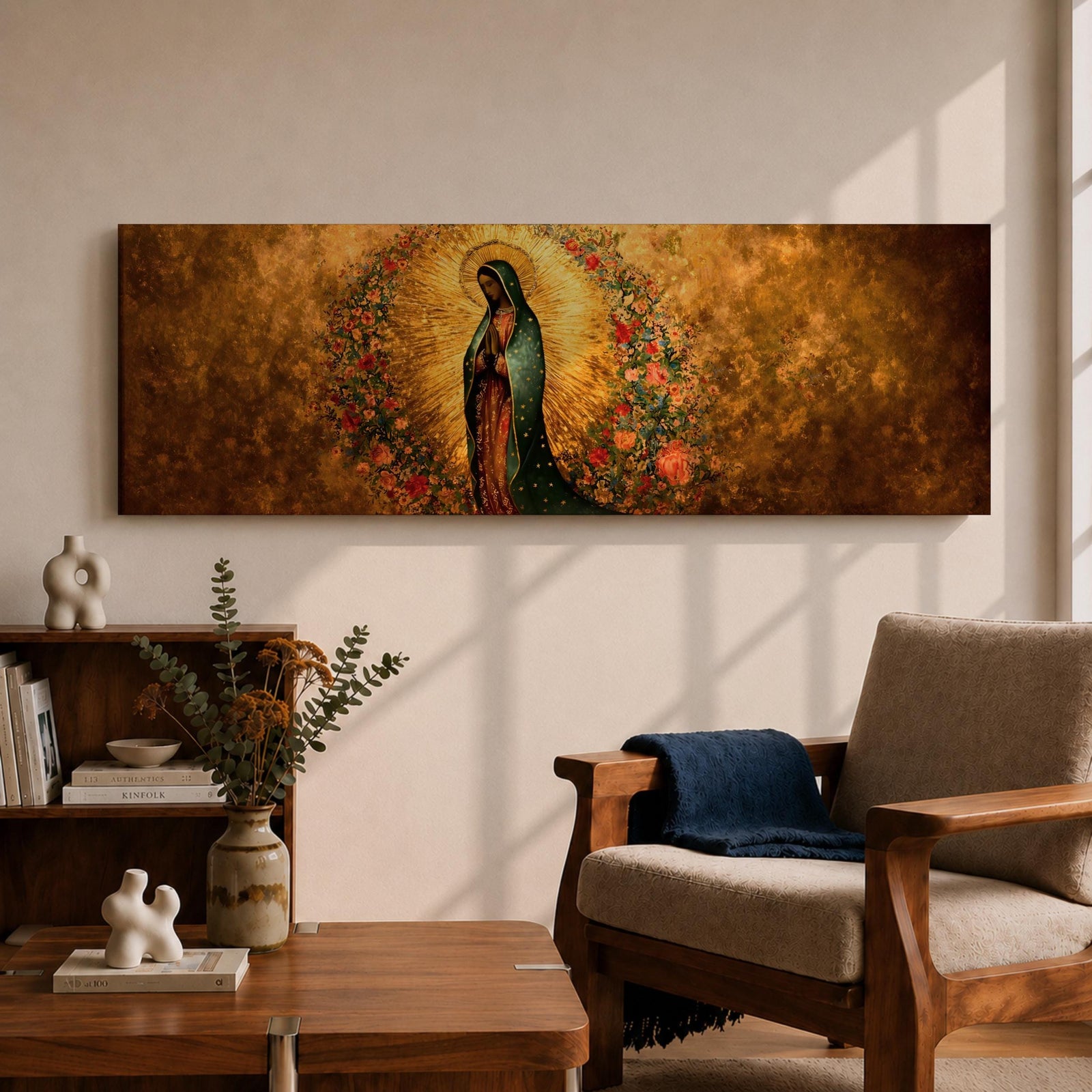 A long panoramic artwork depicting Our Lady of Guadalupe standing in prayer with folded hands and bowed head. She wears a green star covered mantle over a rose colored gown and is surrounded by radiant golden rays and a wreath of vibrant flowers, forming a traditional Catholic Marian image in a wide horizontal composition.
