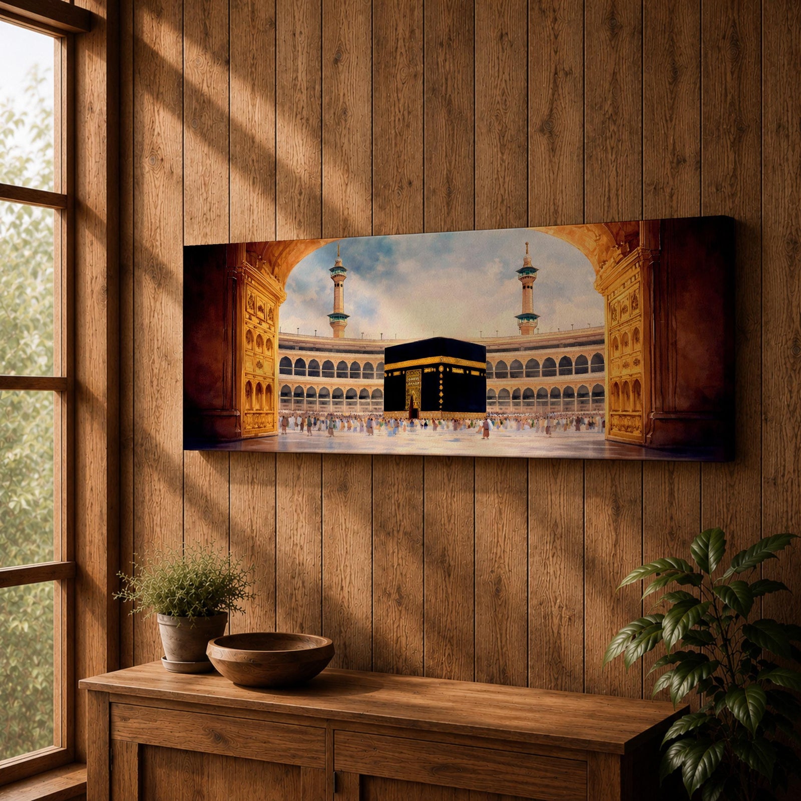 A long panoramic artwork depicting the Kaaba at the center of Masjid Al Haram in Mecca framed by grand mosque arches and tall minarets. The sacred black cube stands in the courtyard while pilgrims gather around it, creating a wide horizontal composition highlighting the holy Islamic sanctuary.