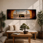 A long panoramic artwork depicting the Kaaba at the center of Masjid Al Haram in Mecca framed by grand mosque arches and tall minarets. The sacred black cube stands in the courtyard while pilgrims gather around it, creating a wide horizontal composition highlighting the holy Islamic sanctuary.