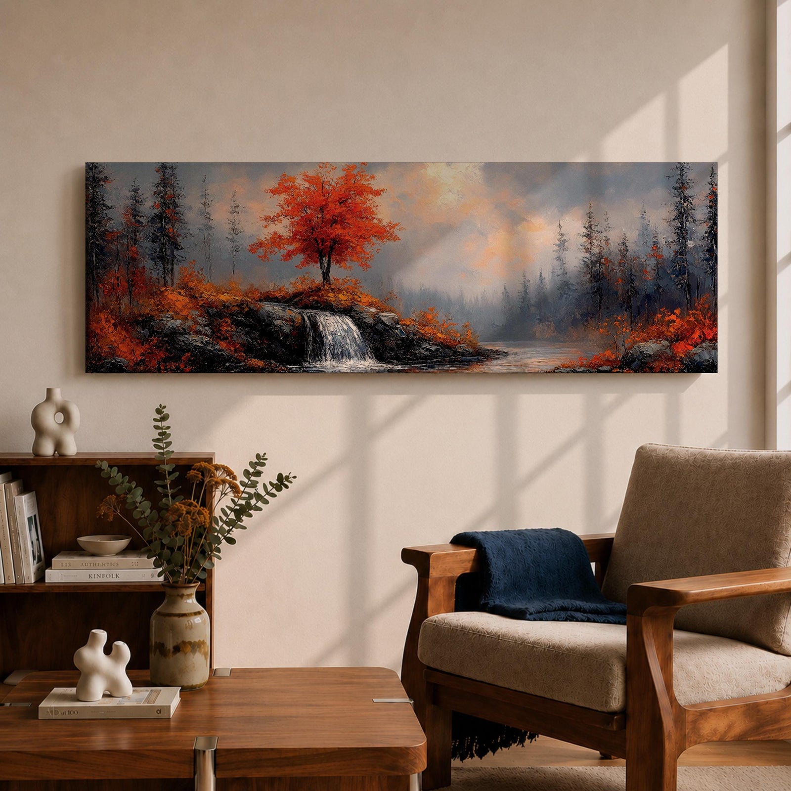 A long panoramic landscape painting showing a small waterfall flowing over rocky cliffs beneath a vivid red autumn tree. Surrounding forest trees fade into misty blue tones while bright fall foliage and rugged stones frame the stream, forming a tranquil woodland scene across a wide horizontal composition.