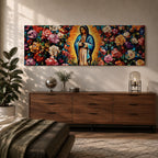 A long panoramic painting of Mary of Guadalupe standing in prayer with hands folded and head bowed, surrounded by radiant golden rays. She wears a blue mantle over a rose colored gown while vibrant roses and colorful flowers fill the background, creating a devotional Catholic Marian image across a wide horizontal composition.