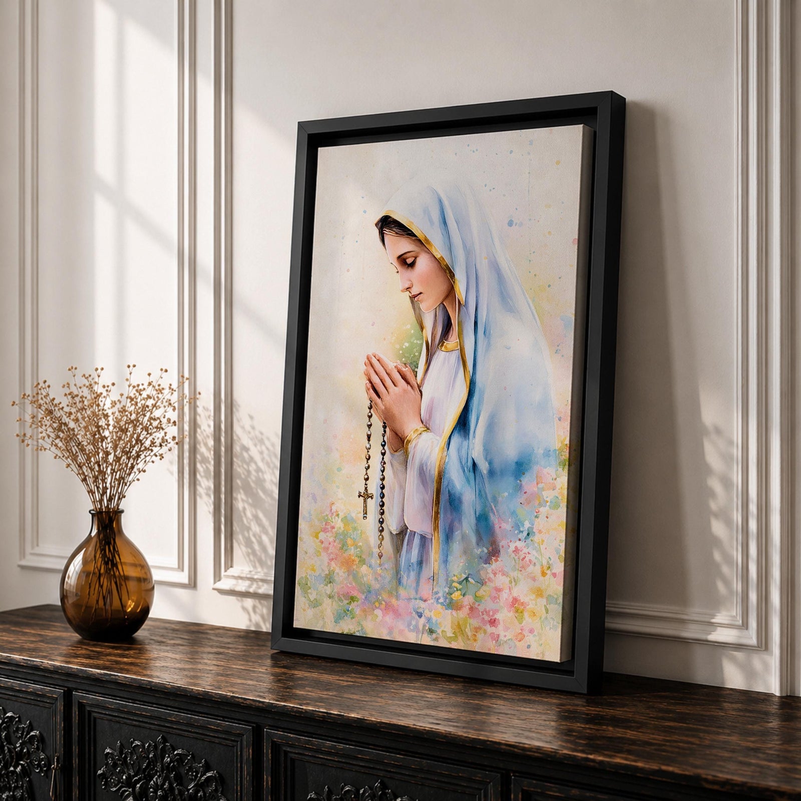 A watercolor style framed canvas depicting Virgin Mary in profile, wearing a blue and white veil with gold trim, holding a rosary and praying, surrounded by soft floral colors and a gentle light background.