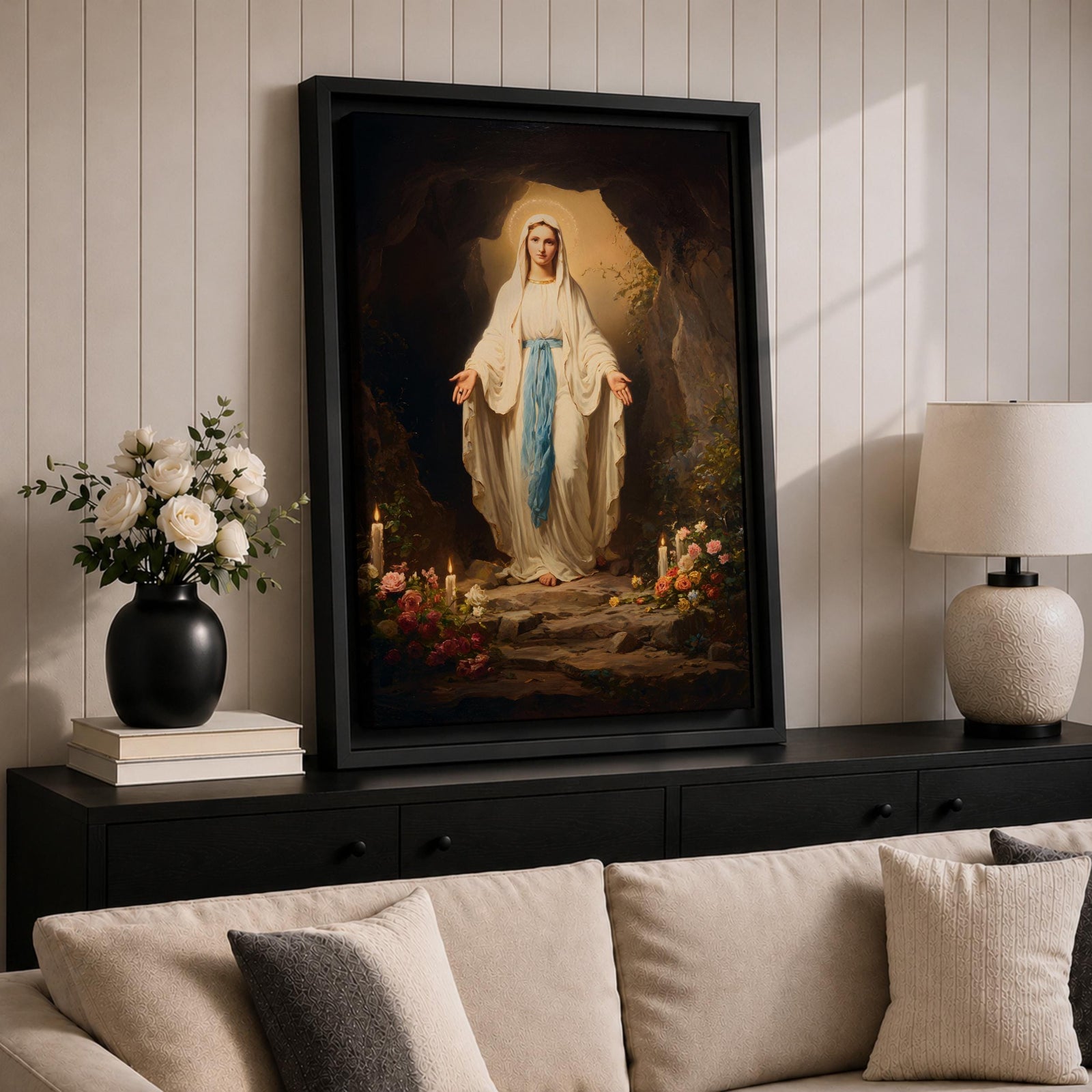 A detailed painting of Our Lady of Lourdes standing at the entrance of a grotto with open arms, dressed in white robes with a blue sash, surrounded by candles and flowers, representing the Marian apparition at Lourdes in a traditional religious style.