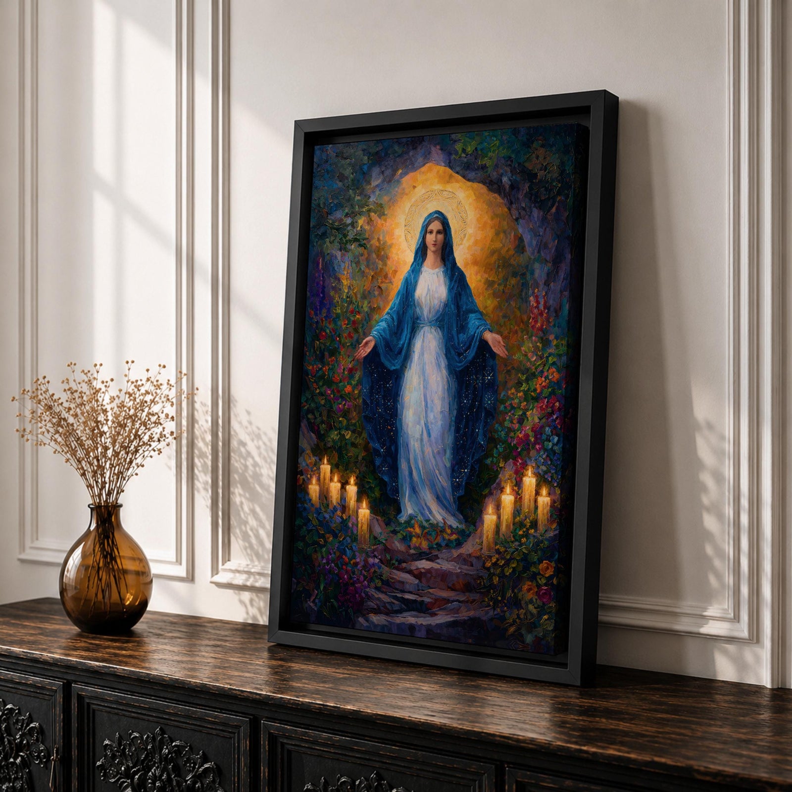 A framed canvas painting of Our Lady of Lourdes depicts the Virgin Mary standing with open arms surrounded by glowing candles and vibrant flowers, rendered in a richly detailed, realistic style with a luminous halo behind her head, evoking a serene and reverent atmosphere.