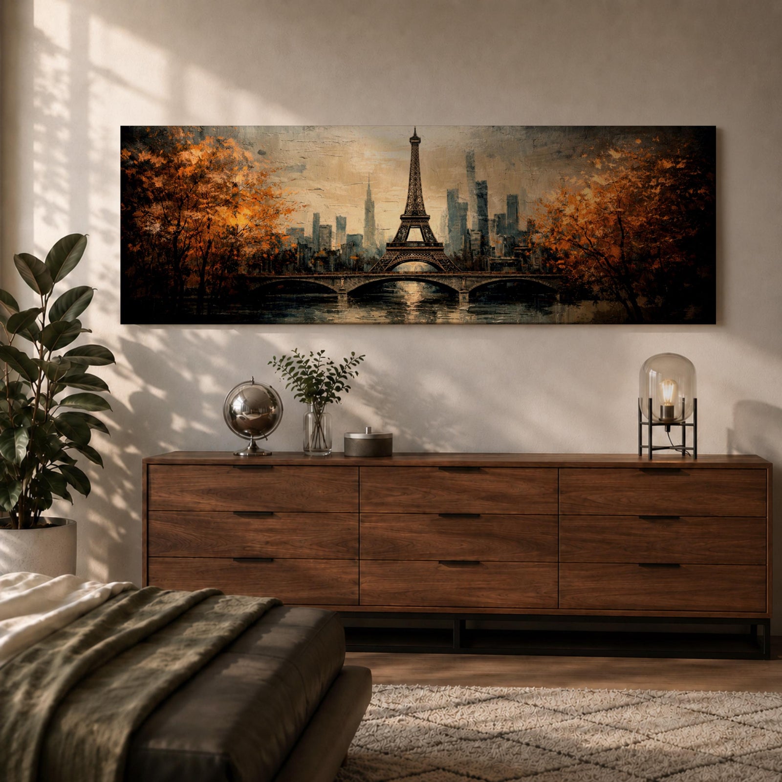 A long narrow panoramic painting depicts the Eiffel Tower rising above a river with an arched bridge in the foreground, surrounded by autumn trees and a distant city skyline, rendered in textured brushstrokes with warm golden tones and soft reflections that create depth and a romantic atmospheric cityscape.