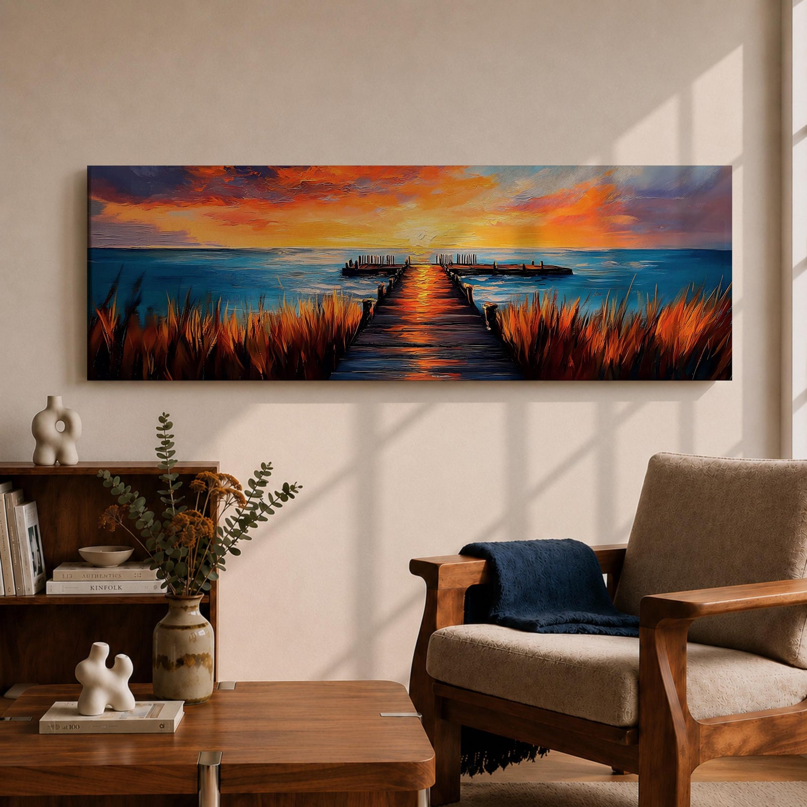 A long narrow panoramic painting depicts a wooden pier extending through tall grasses into calm ocean waters, leading toward a glowing sunset on the horizon, with bold textured brushstrokes and vivid color contrasts capturing reflections of warm light across the water and sky in an expressive contemporary style.