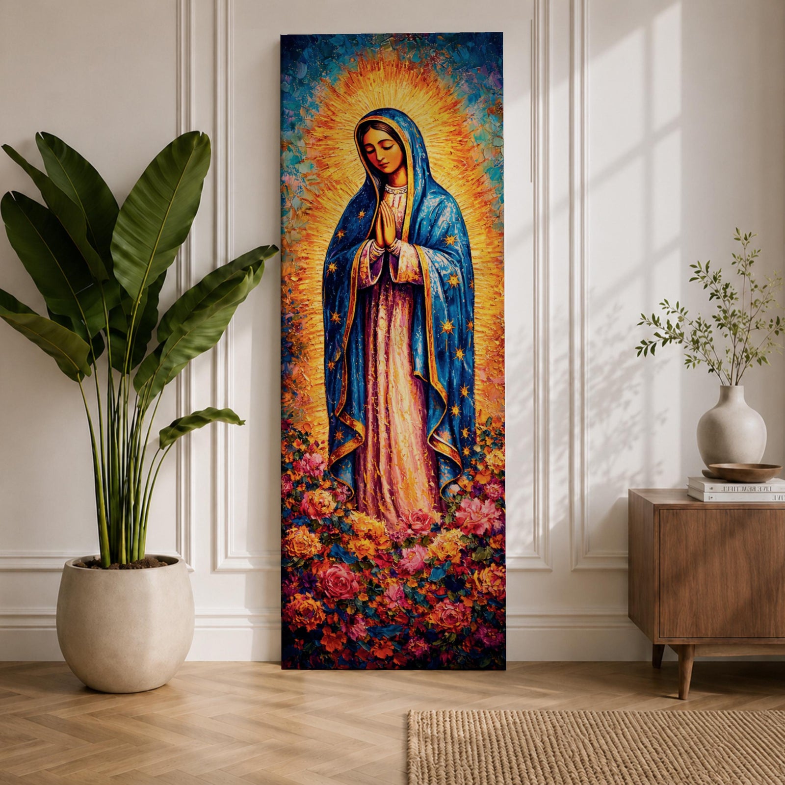 A tall narrow vertical depiction of Our Lady of Guadalupe standing in prayer with hands clasped, wearing a blue star covered mantle and soft pink gown, surrounded by a radiant golden sunburst and dense vibrant floral arrangement at her feet, rendered with rich texture and layered color in a devotional composition.