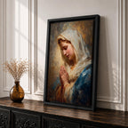 Sacred Catholic wall art featuring the Virgin Mary in prayer with hands clasped and eyes gently lowered. Soft golden light illuminates her serene expression, while rich blue garments and impressionist brushwork create a timeless devotional portrait ideal for prayer rooms and Christian homes.