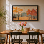 A framed abstract painting of an autumn forest landscape featuring tall slender trees with orange and red foliage and a muted mountain backdrop. The composition uses textured brush strokes to create a modern impression of fall trees in a natural setting.