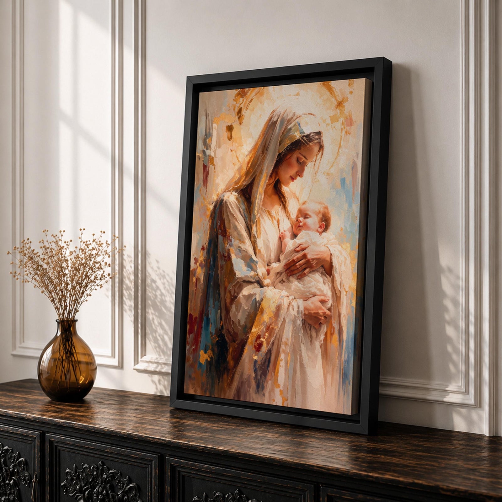 A framed canvas painting depicting Madonna and Child, showing the Virgin Mary tenderly holding baby Jesus. The artwork features soft brush strokes and warm tones, emphasizing the loving bond between mother and child in a classical religious style.