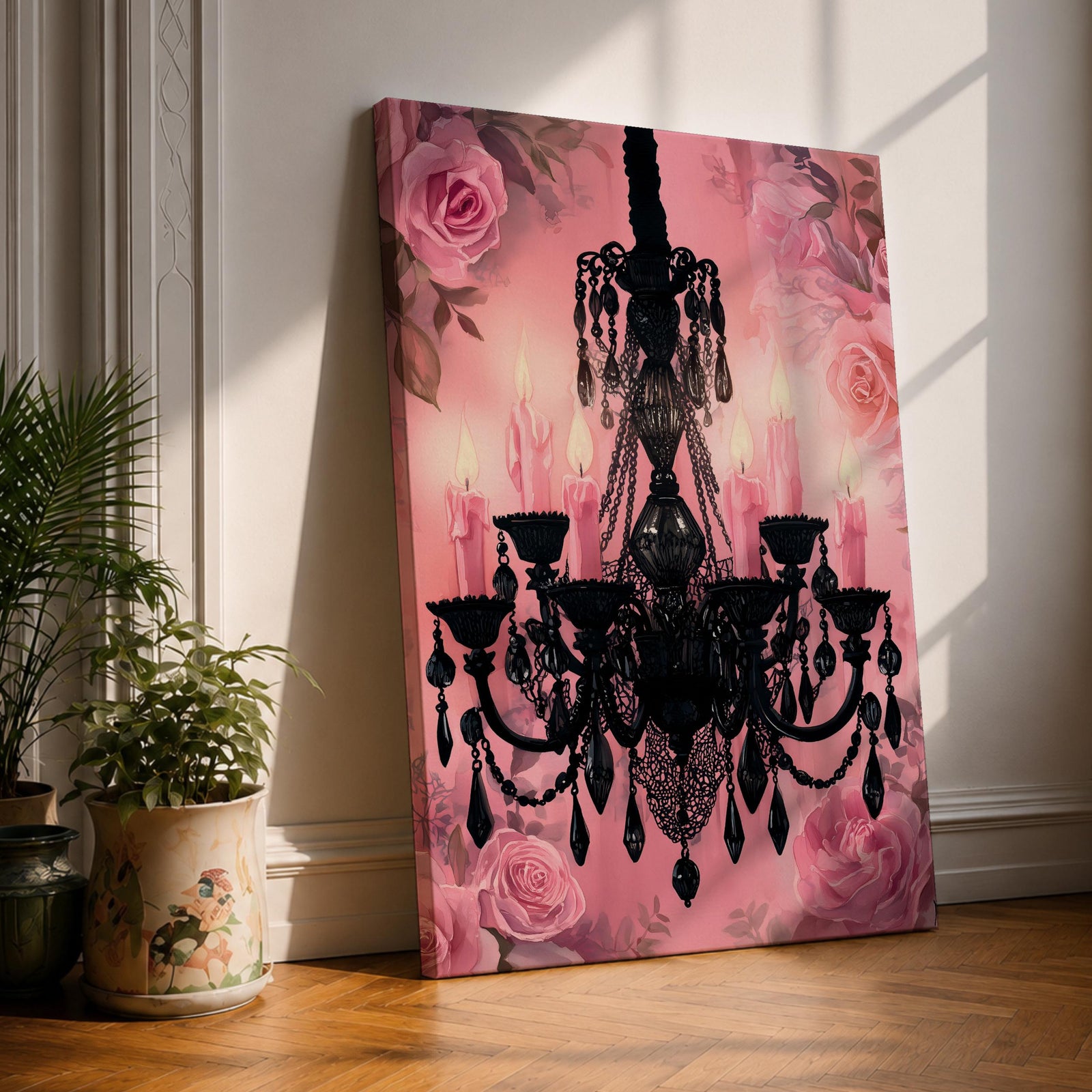 A framed canvas print featuring a detailed black chandelier silhouette with multiple hanging crystals and candle flames, set against a pink floral background with roses, blending ornate lighting design with a soft botanical motif.