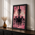 A framed canvas print featuring a detailed black chandelier silhouette with multiple hanging crystals and candle flames, set against a pink floral background with roses, blending ornate lighting design with a soft botanical motif.