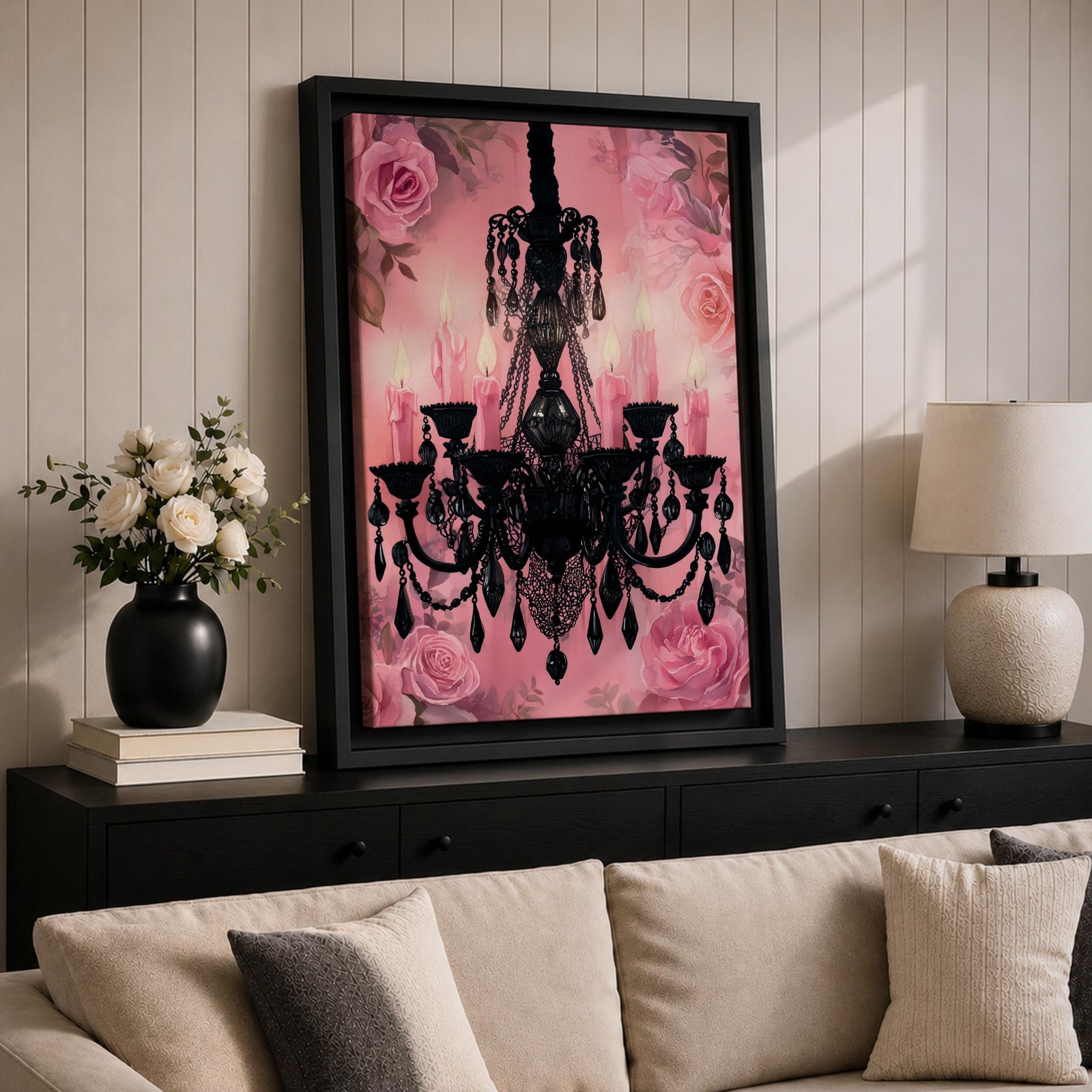 A framed canvas print featuring a detailed black chandelier silhouette with multiple hanging crystals and candle flames, set against a pink floral background with roses, blending ornate lighting design with a soft botanical motif.