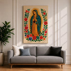 A framed stitched style art print depicting Our Lady of Guadalupe with hands clasped in prayer, surrounded by a radiant golden halo and vibrant floral embroidery in red, blue, and green. The image captures the traditional Mexican Catholic iconography with intricate textile detail and a serene expression.