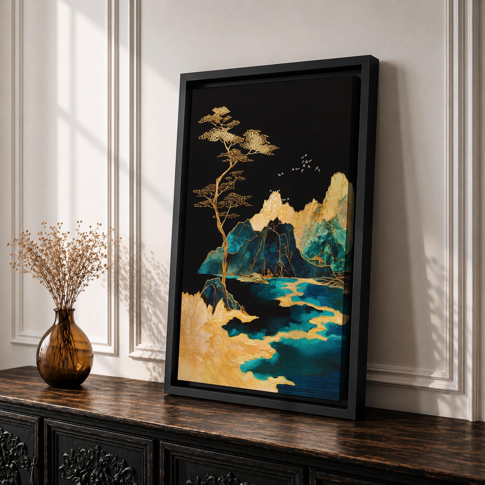 A framed canvas artwork depicting a mountain landscape with abstract golden and teal elements. The composition features stylized mountains, a flowing river, and a tall tree with birds flying above, rendered in an abstract style with rich gold and blue tones against a dark background.