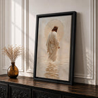A framed canvas artwork depicting Jesus walking on water, showing him in a flowing robe with rippling water beneath and a glowing halo behind his head. The style is realistic with textured brush strokes emphasizing the water’s movement and the figure’s serene posture.