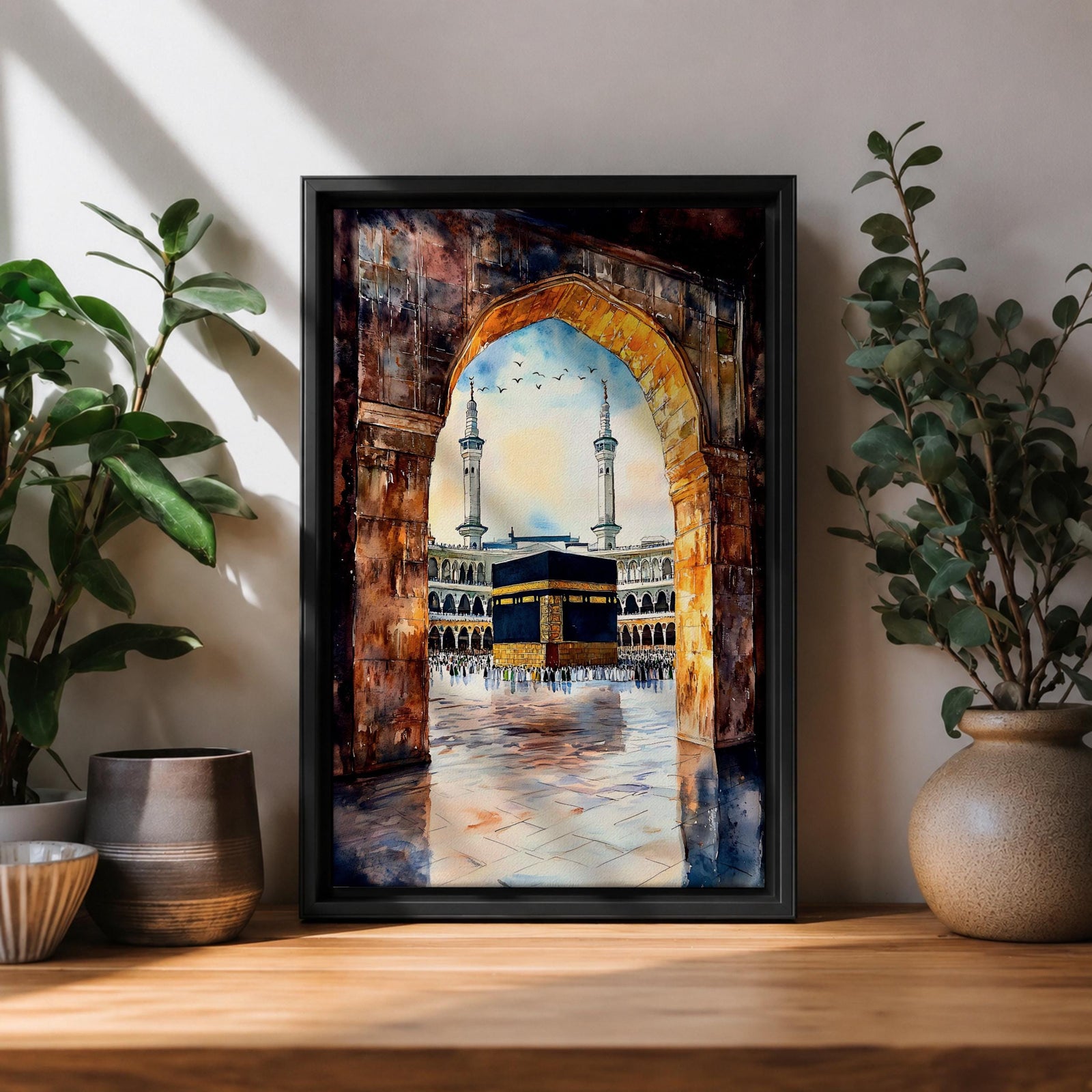 Watercolor-style painting of the Kaaba in Masjid al-Haram viewed through a large stone archway, showing the sacred courtyard with pilgrims and two tall minarets rising above the mosque.