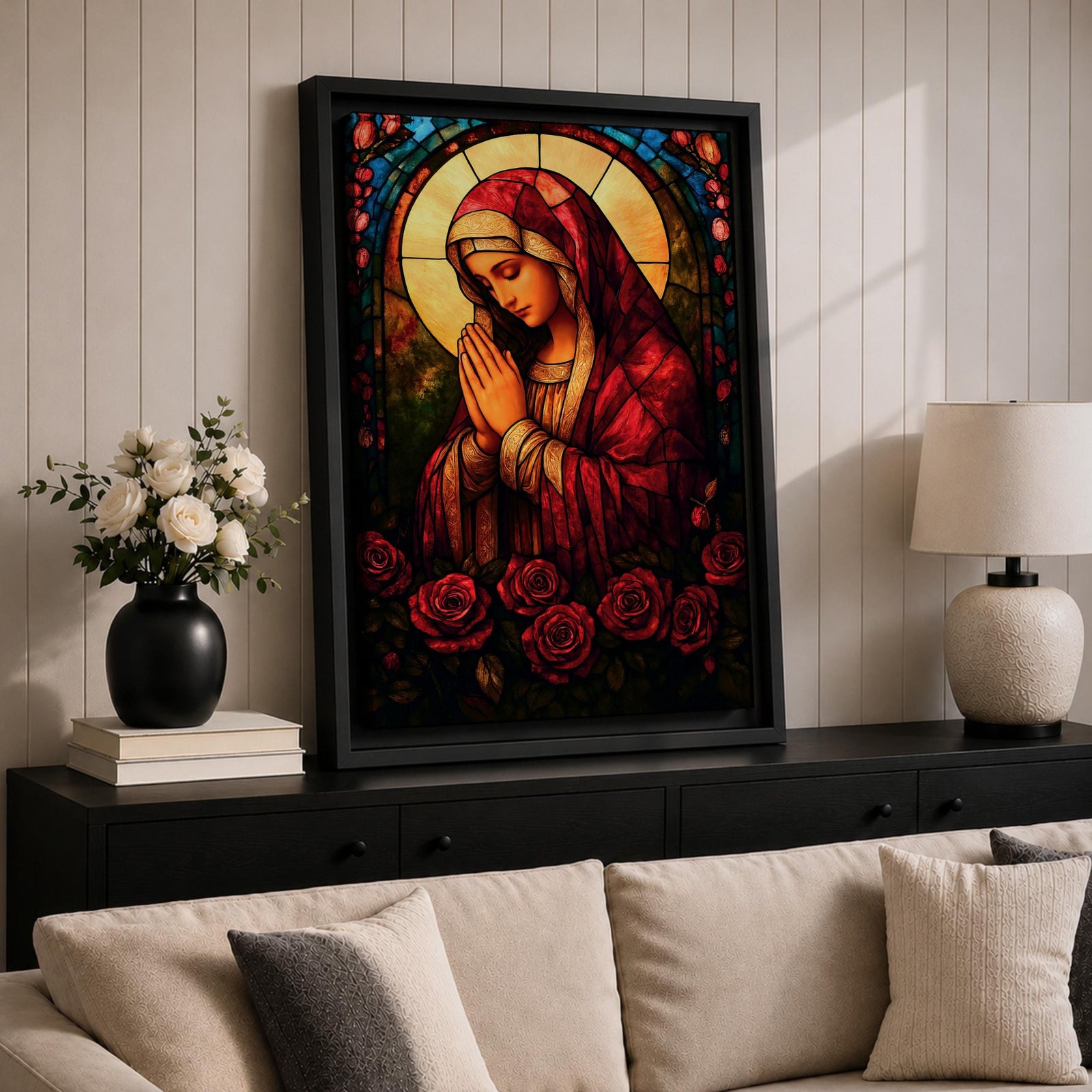 A stained glass style artwork depicting the Virgin Mary in a red robe with hands clasped in prayer, surrounded by a glowing halo and red roses at the bottom. The piece features intricate glass-like segments and rich colors, capturing a classic religious stained glass window aesthetic.