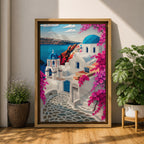 A vibrant framed canvas depicting Santorini, Greece, featuring iconic white buildings with blue domes, winding cobblestone paths, and bright bougainvillea flowers overlooking a deep blue sea, rendered in a clean, graphic style emphasizing architectural shapes and Mediterranean coastal charm.