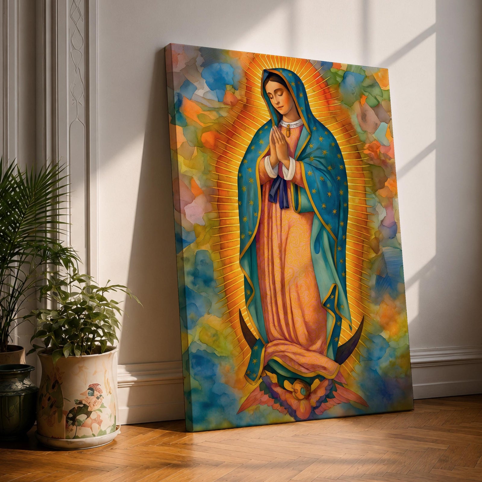 A vibrant framed canvas depicting Our Lady of Guadalupe, showing the Virgin Mary with hands clasped in prayer, wearing a blue mantle adorned with stars and a pink dress, surrounded by radiant golden rays and a colorful abstract background.