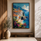 This impasto style framed canvas depicts the Amalfi Coast featuring a cluster of Italian villas with terracotta roofs perched on cliffs overlooking a vibrant blue Mediterranean sea under a partly cloudy sky, with colorful flowers in the foreground enhancing the coastal landscape scene.