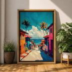 A vibrant painting depicting a tropical beach village with colorful houses lining a descending street toward the ocean. Palm trees rise above the rooftops under a bright blue sky with fluffy clouds. The artwork captures a lively coastal town atmosphere in a bold, illustrative style.