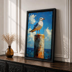 A framed canvas painting of a seagull perched on a weathered post against a bright blue sky with fluffy clouds and a distant ocean horizon. The artwork captures the bird in a realistic style with textured brushstrokes emphasizing the natural coastal scene.