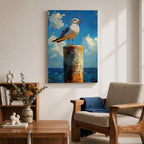 A framed canvas painting of a seagull perched on a weathered post against a bright blue sky with fluffy clouds and a distant ocean horizon. The artwork captures the bird in a realistic style with textured brushstrokes emphasizing the natural coastal scene.