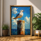 A framed canvas painting of a seagull perched on a weathered post against a bright blue sky with fluffy clouds and a distant ocean horizon. The artwork captures the bird in a realistic style with textured brushstrokes emphasizing the natural coastal scene.