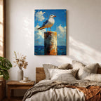 A framed canvas painting of a seagull perched on a weathered post against a bright blue sky with fluffy clouds and a distant ocean horizon. The artwork captures the bird in a realistic style with textured brushstrokes emphasizing the natural coastal scene.