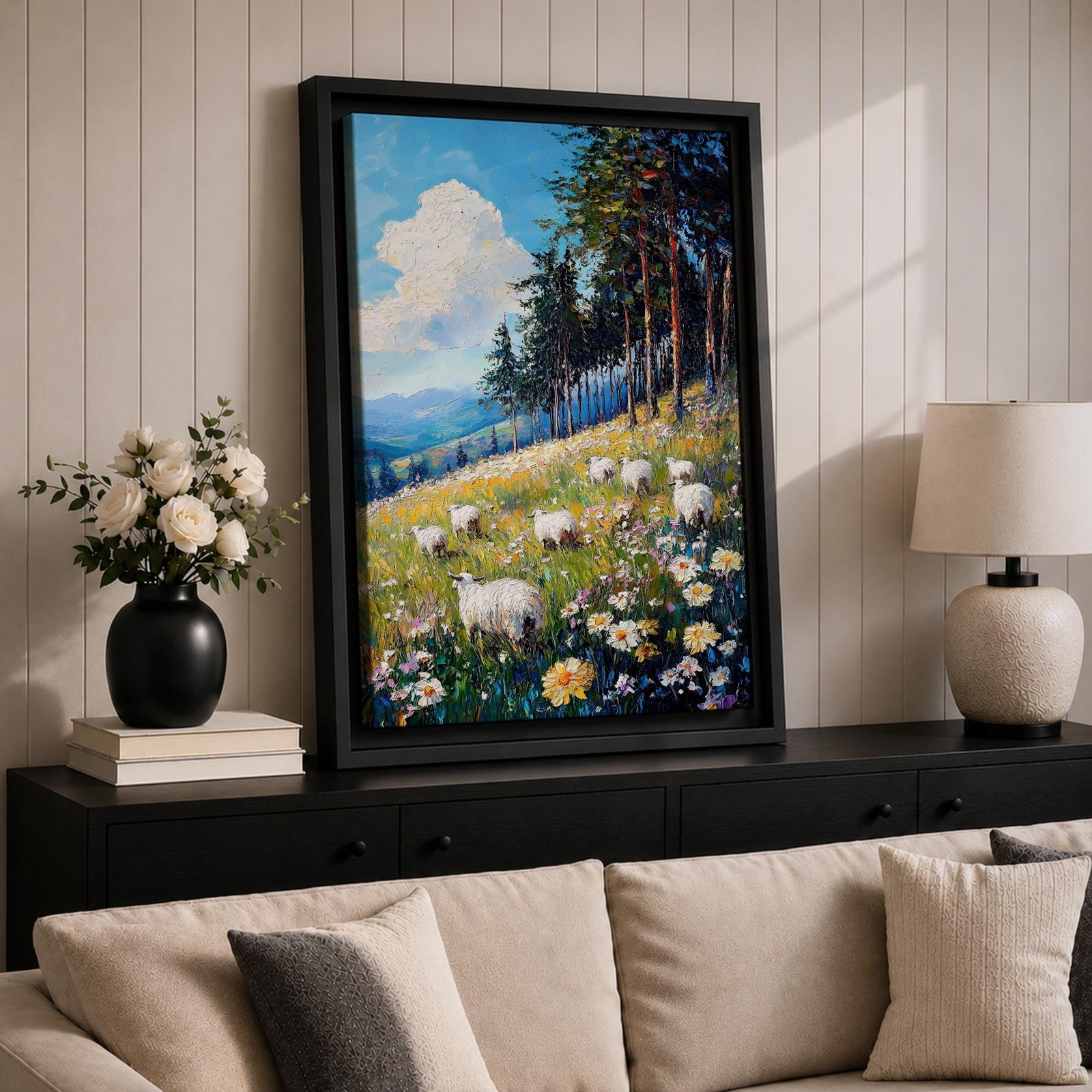 This impasto style framed canvas depicts a scenic landscape of sheep grazing in a meadow filled with wildflowers, bordered by tall trees and distant mountains under a bright blue sky with fluffy clouds, rendered with thick textured brushstrokes that emphasize the natural rustic setting.
