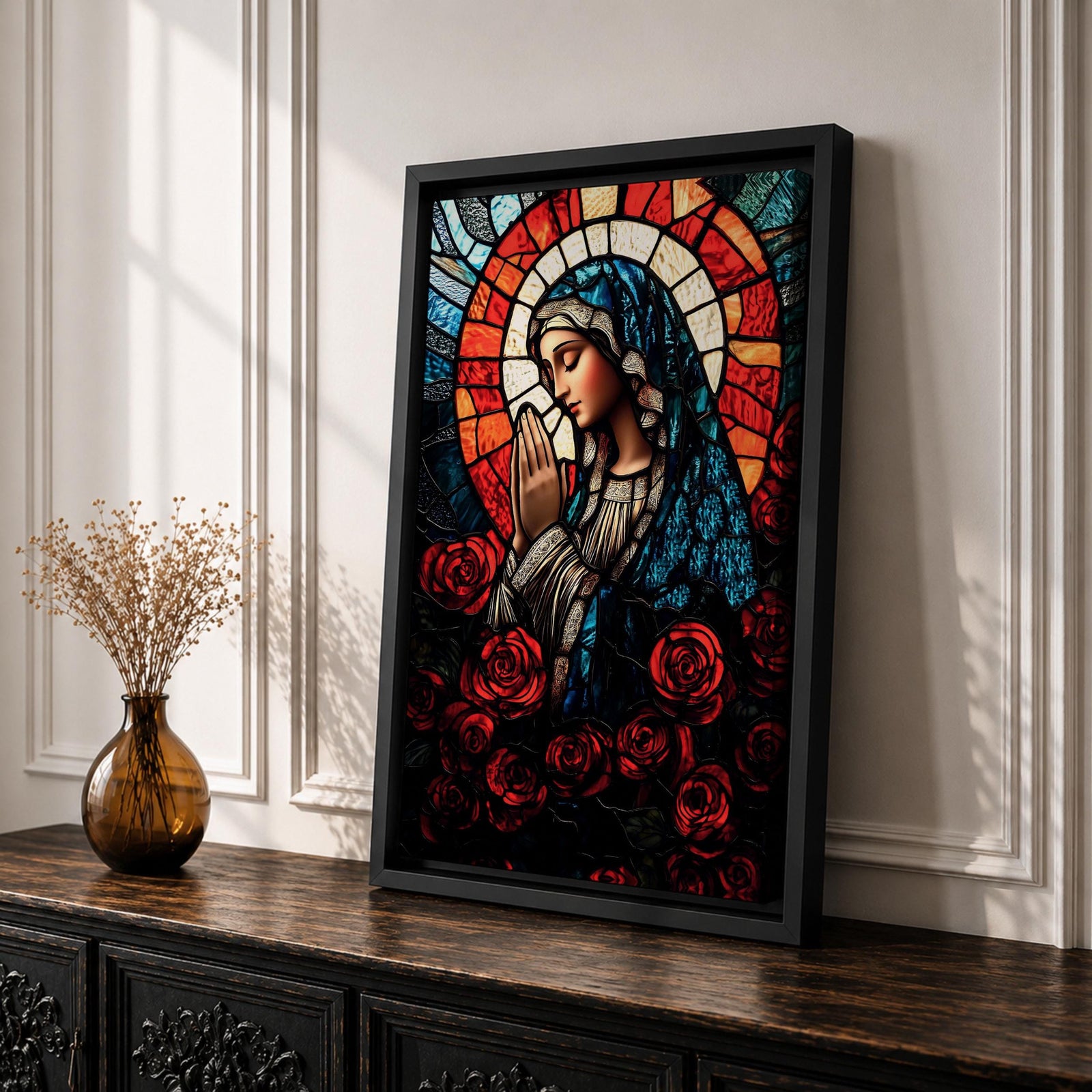 A stained glass style depiction of Virgin Mary with hands clasped in prayer, surrounded by red roses and a radiant halo behind her head. The image uses vibrant colors and intricate glass-like textures to create a mosaic effect emphasizing religious devotion and reverence.