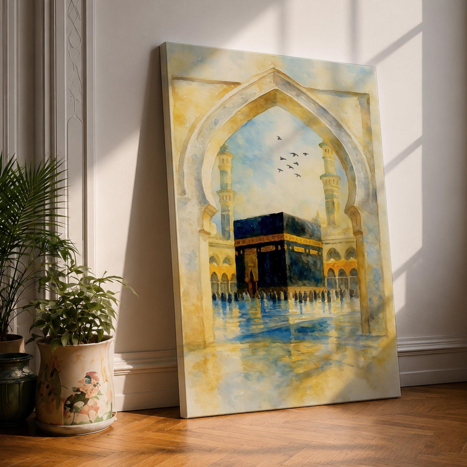 Soft watercolor artwork of the Kaaba at Masjid Al Haram framed by a Moorish pointed arch with mosque minarets and birds flying above the reflective courtyard.