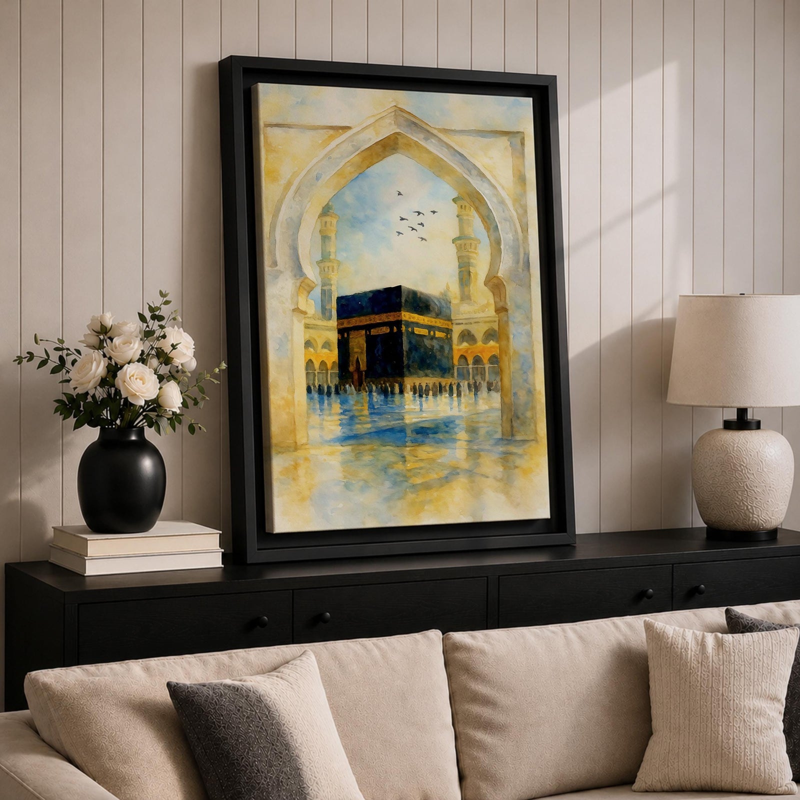 Soft watercolor artwork of the Kaaba at Masjid Al Haram framed by a Moorish pointed arch with mosque minarets and birds flying above the reflective courtyard.
