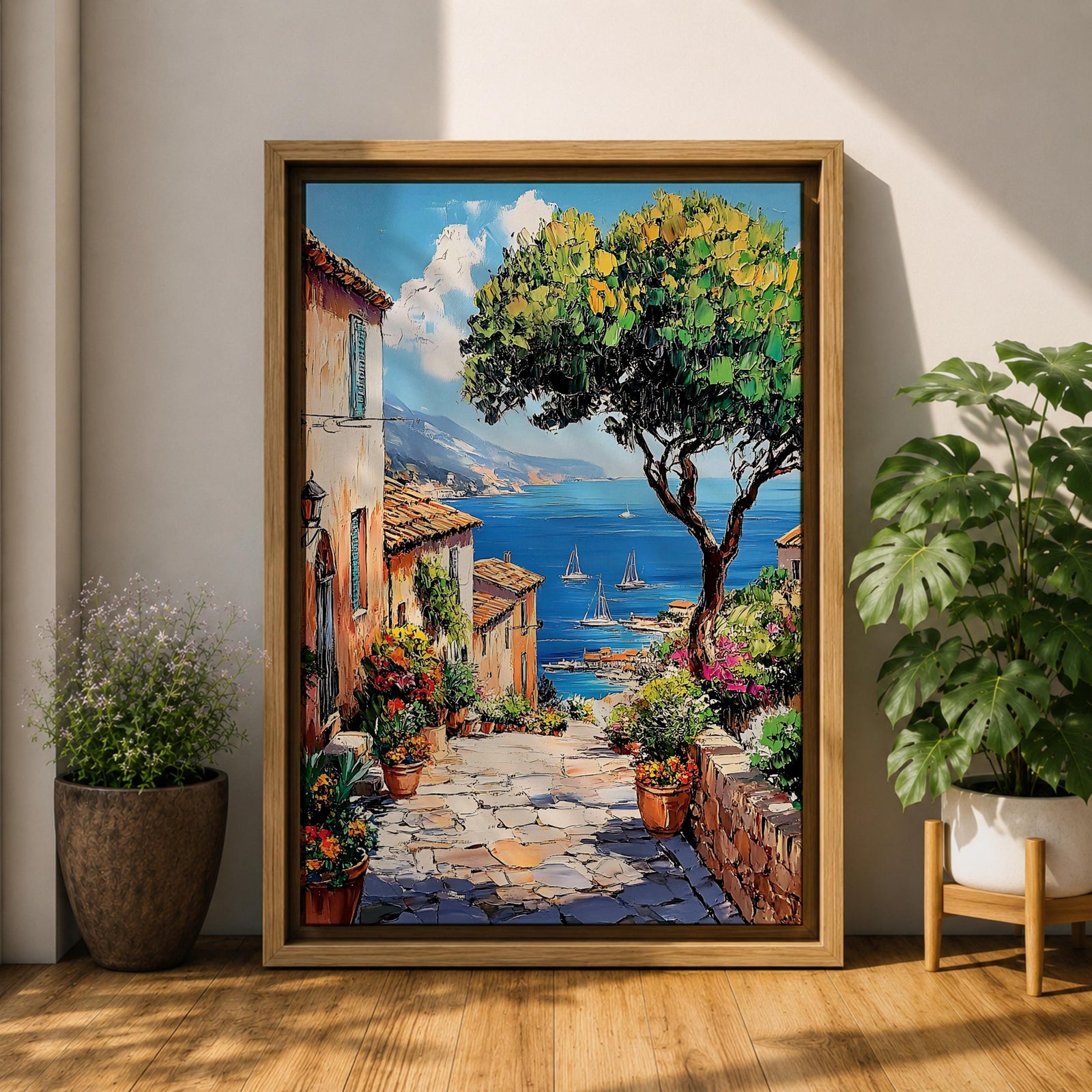 A vibrant framed canvas painting depicting a charming coastal village with stone-paved streets, terracotta rooftops, lush greenery, colorful flowers, and sailboats on a deep blue sea under a clear sky, rendered in a detailed, realistic style capturing Mediterranean summer ambiance.