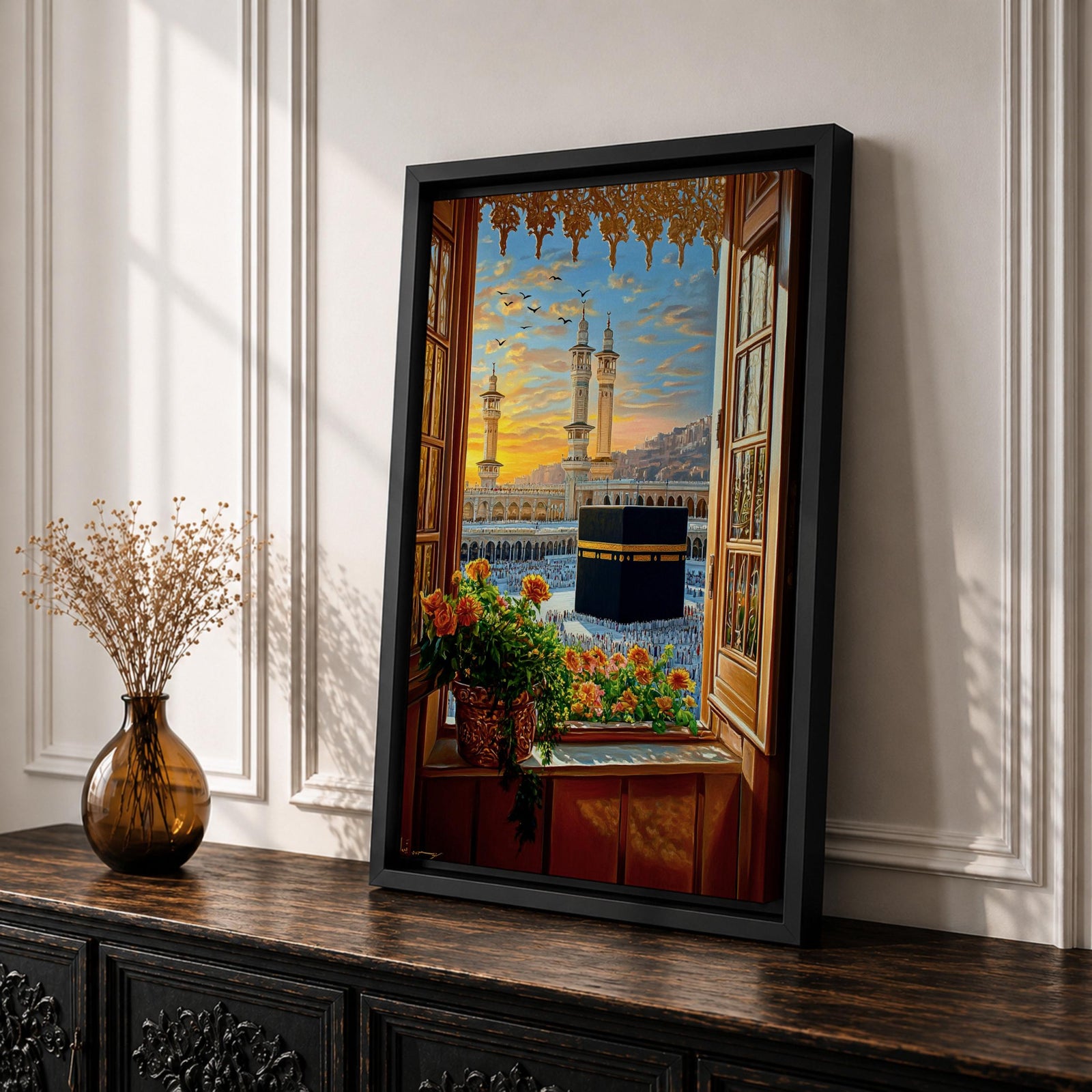 Painting of the Kaaba at Masjid Al Haram in Mecca viewed through an open wooden window with flowers on the sill, showing the black Kaaba in the courtyard surrounded by worshippers and tall mosque minarets under a glowing sunset sky.