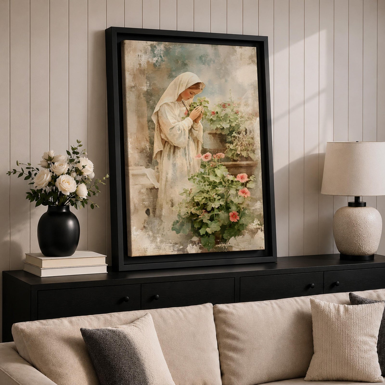 Soft vintage style painting of the Virgin Mary standing in prayer beside blooming garden flowers, wearing a white veil and robe while gently holding a small blossom, surrounded by pastel greenery and delicate pink flowers in a serene devotional garden scene.